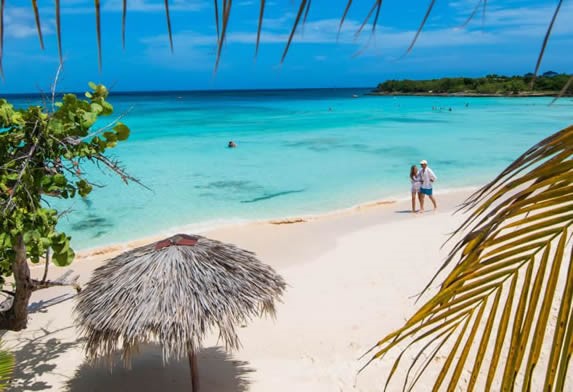 tourists walking along the blue water beach