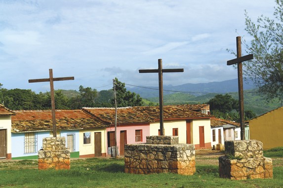 monument of three wooden crosses on the grass.
