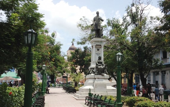 plaza rodeada de vegetación con estatua de bronce