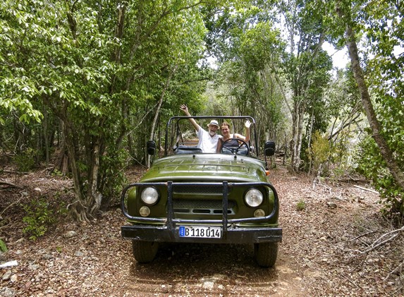 tourists in a jeep surrounded by greenery