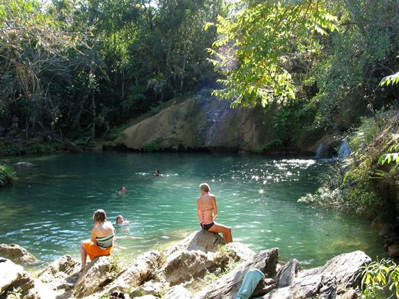 tourists bathing in the waterfall with stones