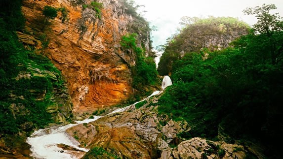 cascada rodeada de piedras y vegetación 