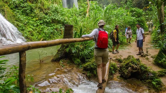 turistas cruzando un riachuelo en un sendero 