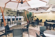 terrace with bar and tables under white umbrellas
