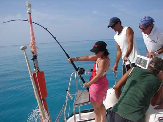 turistas sujetando cañas de pescar en el mar